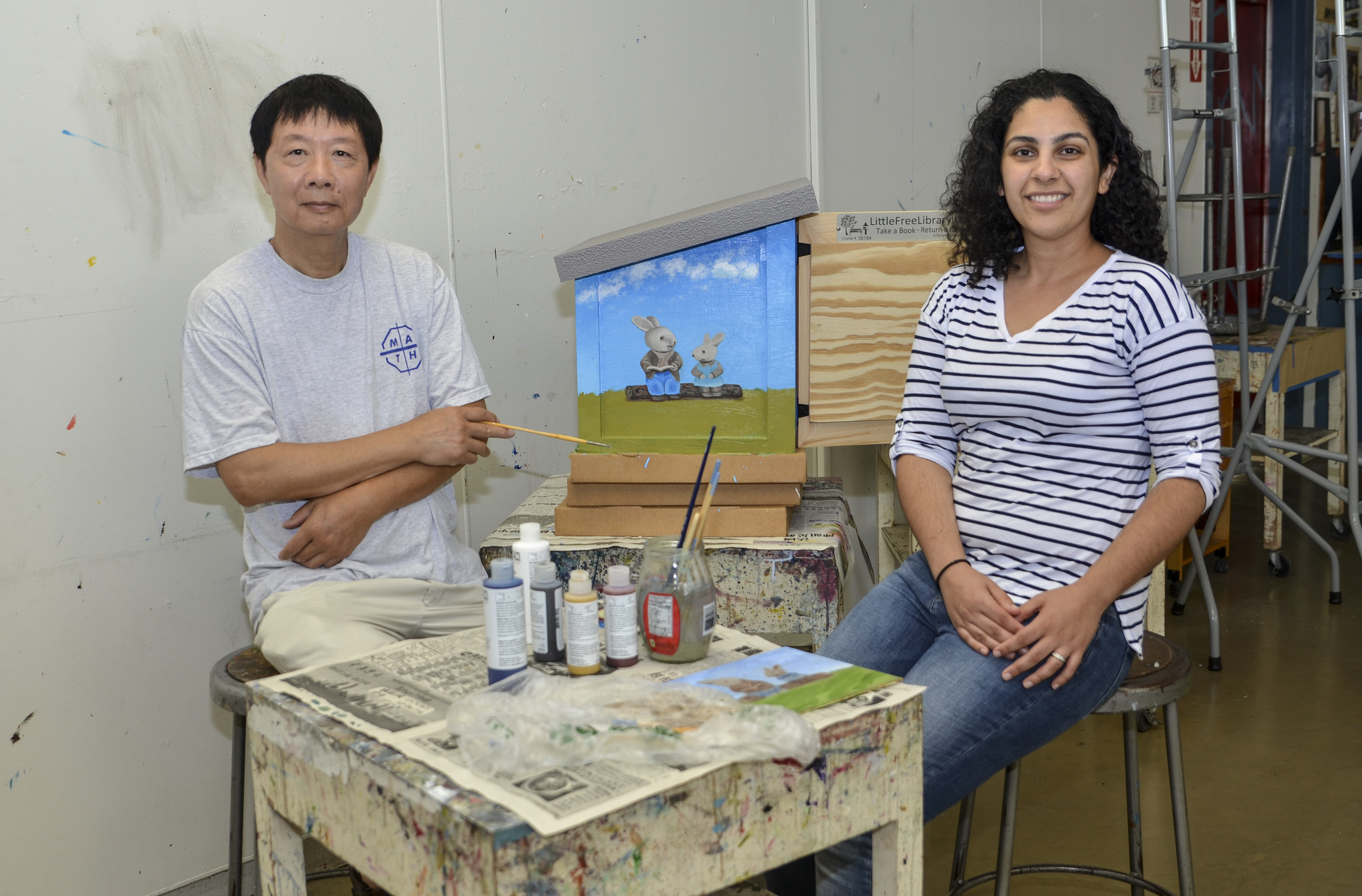 Sam Lee and Pegah Motaleb sit next to the new Mesa supported Little Free Library as Lee adds final touches on the design.