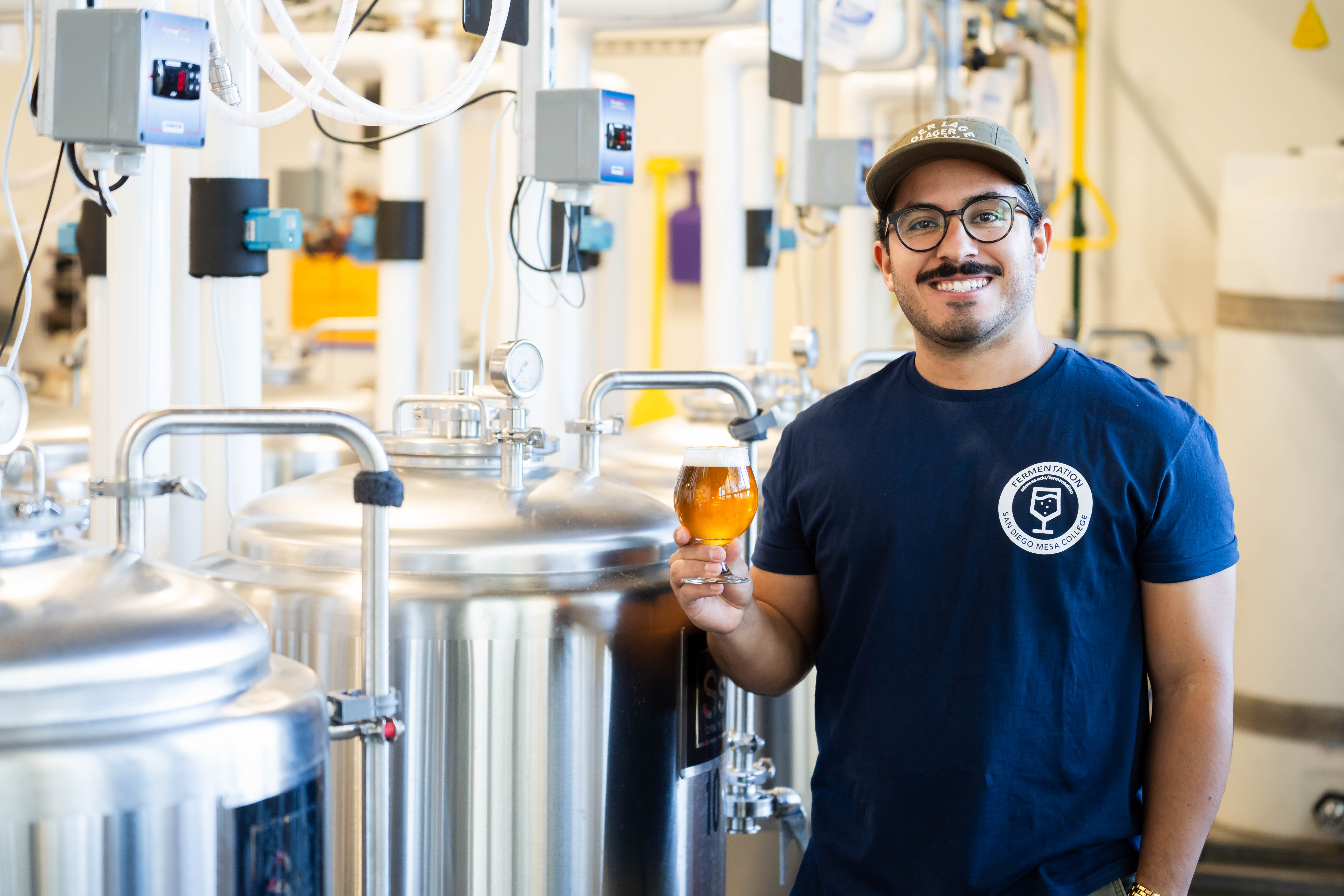 Professor Leguizamon poses with beer next to fermentation equipment